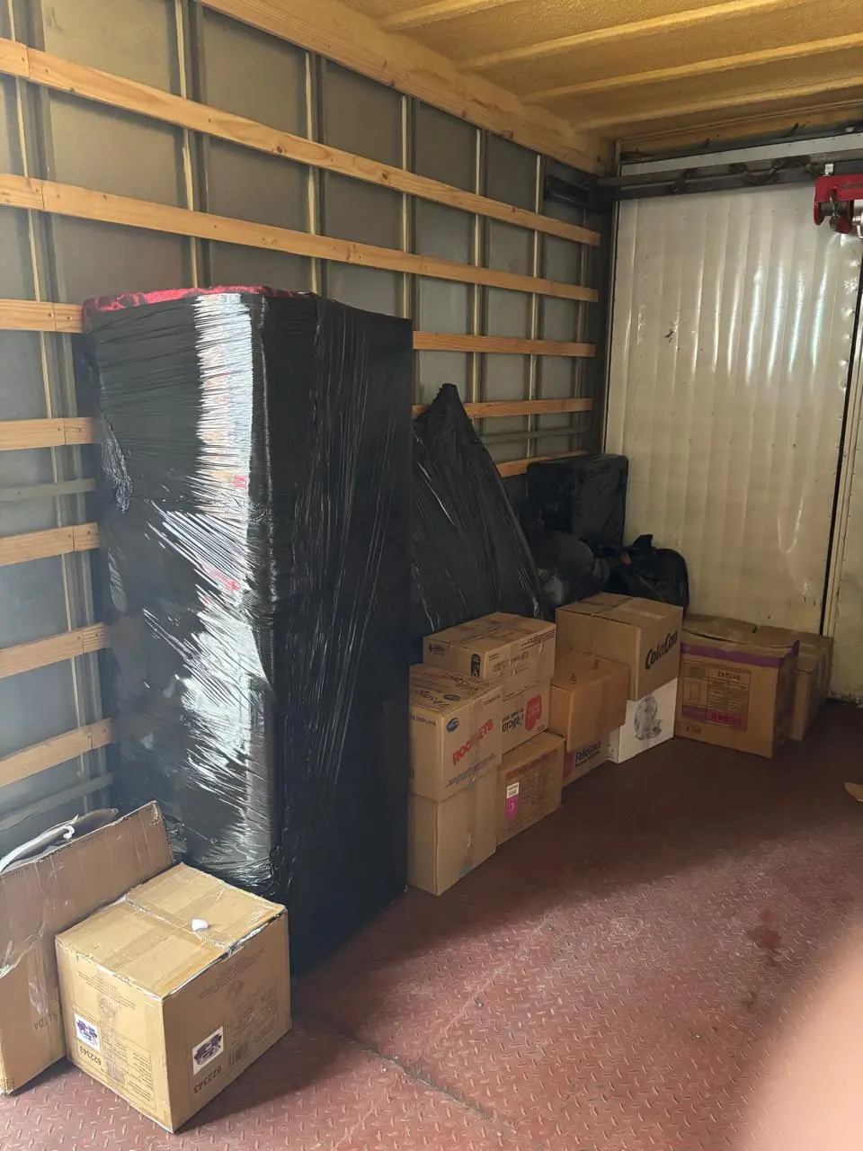 Dos trabajadores de mudanza cargando muebles envueltos